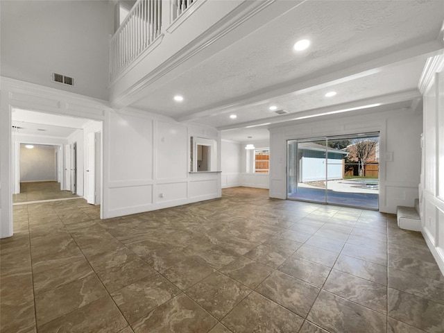 empty room featuring recessed lighting, visible vents, beam ceiling, and a decorative wall