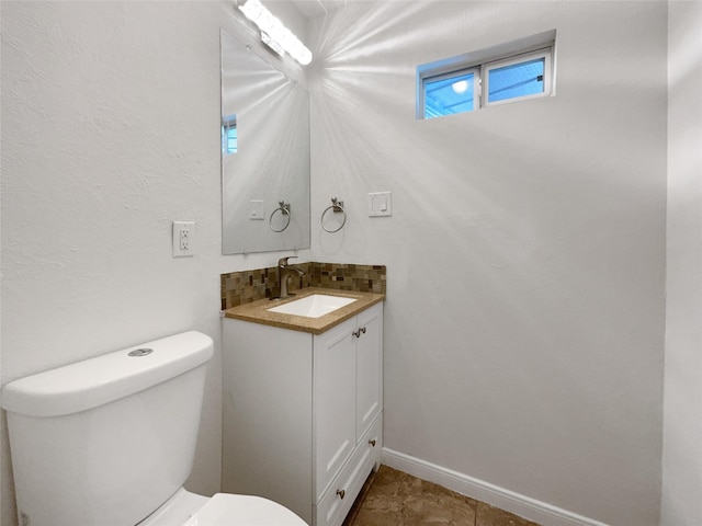 half bath featuring baseboards, toilet, and vanity