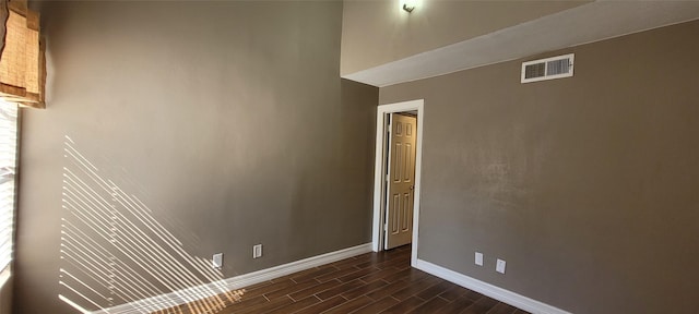 empty room with wood tiled floor, visible vents, and baseboards