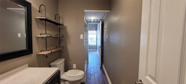 bathroom with baseboards, vanity, toilet, and wood finished floors