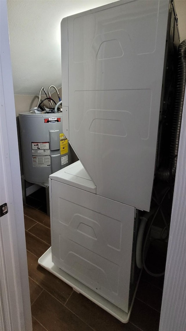 laundry area featuring laundry area, wood tiled floor, electric water heater, and stacked washer / drying machine