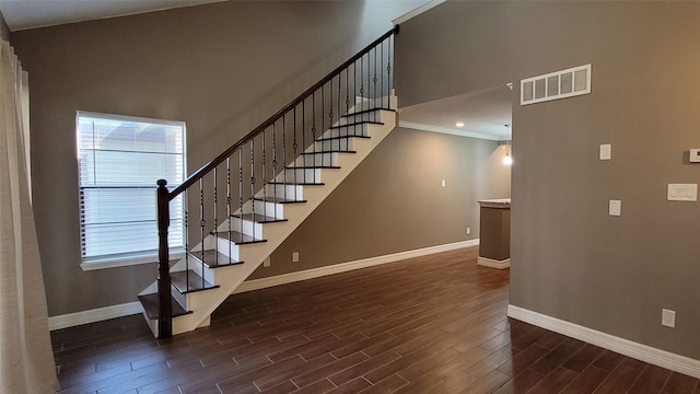 staircase with baseboards, visible vents, and wood finished floors