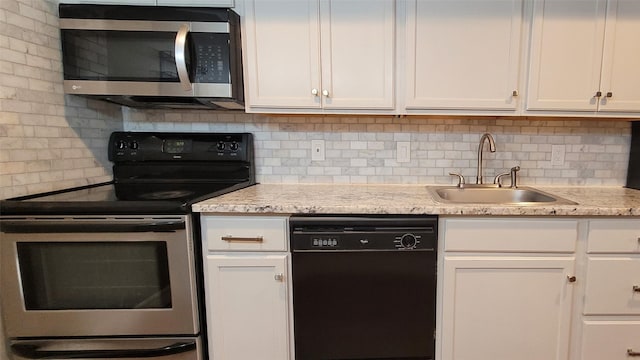 kitchen featuring appliances with stainless steel finishes, white cabinetry, a sink, and tasteful backsplash