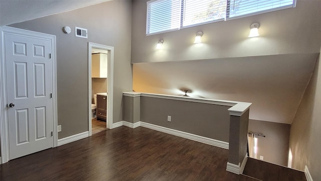 spare room with vaulted ceiling, dark wood-style flooring, and visible vents