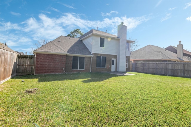 back of property with a lawn, a fenced backyard, a chimney, roof with shingles, and brick siding