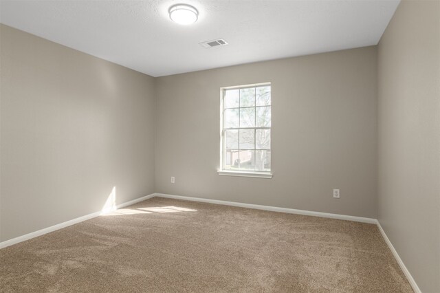 empty room with carpet floors, visible vents, and baseboards