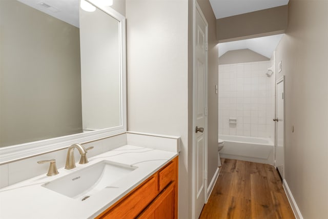 full bath featuring visible vents, toilet, wood finished floors, vanity, and washtub / shower combination