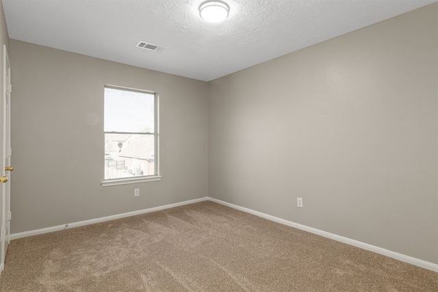 carpeted empty room featuring visible vents, a textured ceiling, and baseboards