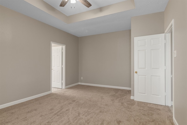 unfurnished bedroom featuring a raised ceiling, carpet flooring, and baseboards