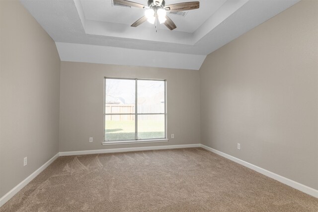 spare room featuring carpet floors, a tray ceiling, baseboards, and a ceiling fan