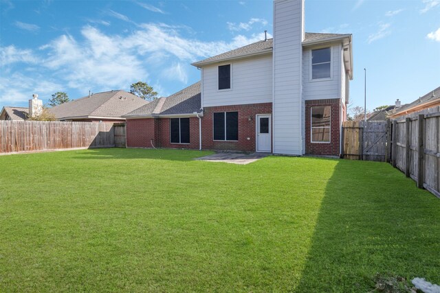 back of property featuring brick siding, a patio, a chimney, a lawn, and a fenced backyard