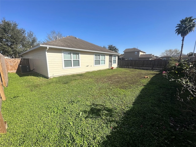 back of house with cooling unit, a fenced backyard, a lawn, and roof with shingles