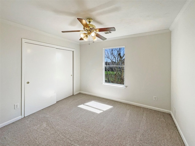 unfurnished bedroom with visible vents, carpet, a ceiling fan, a closet, and crown molding
