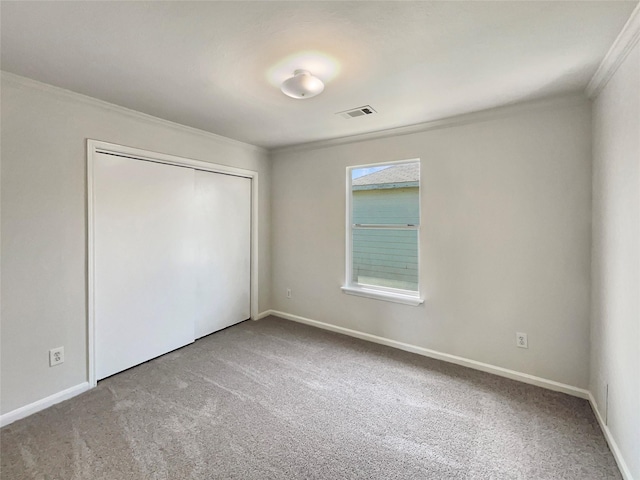 unfurnished bedroom with carpet floors, ornamental molding, visible vents, and a closet