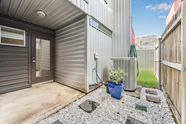 view of exterior entry featuring a patio area, central AC unit, and fence