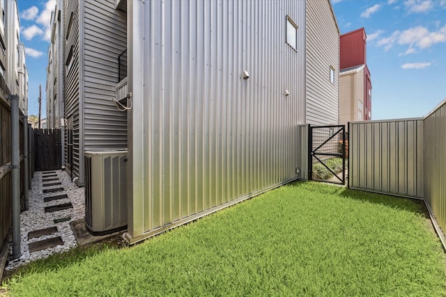 view of yard with cooling unit, a fenced backyard, and a gate