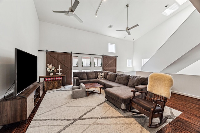 living area with a towering ceiling, a barn door, and wood finished floors