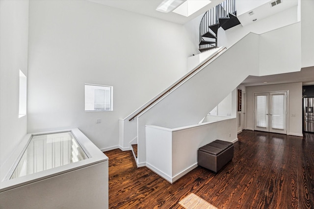 stairs with visible vents, wood finished floors, baseboards, and a towering ceiling