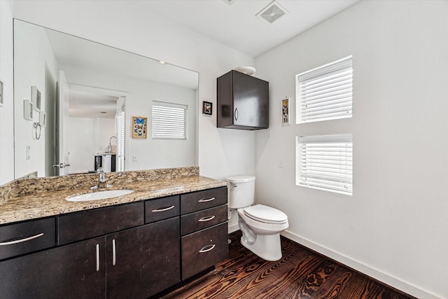 bathroom featuring visible vents, toilet, wood finished floors, baseboards, and vanity