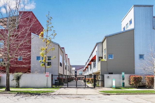 view of road with sidewalks, a residential view, curbs, and a gate