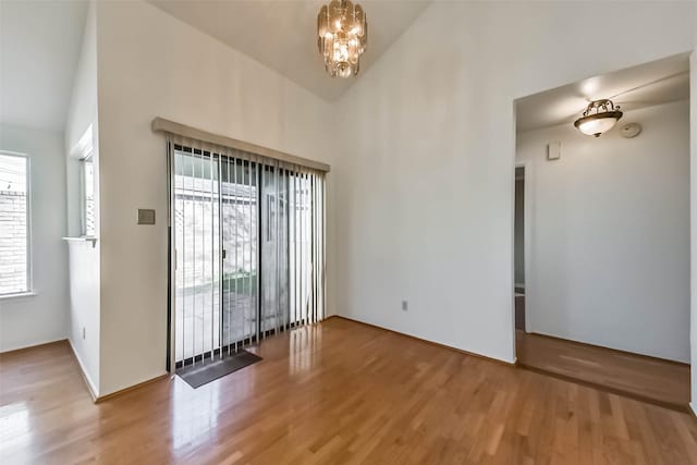 interior space with high vaulted ceiling, wood finished floors, and a chandelier