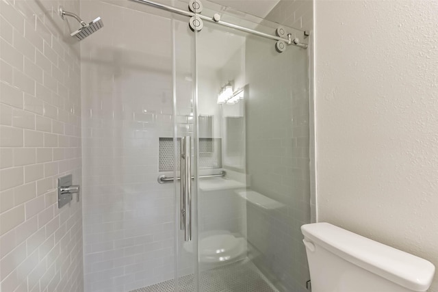 bathroom with a shower stall, toilet, and tile patterned floors