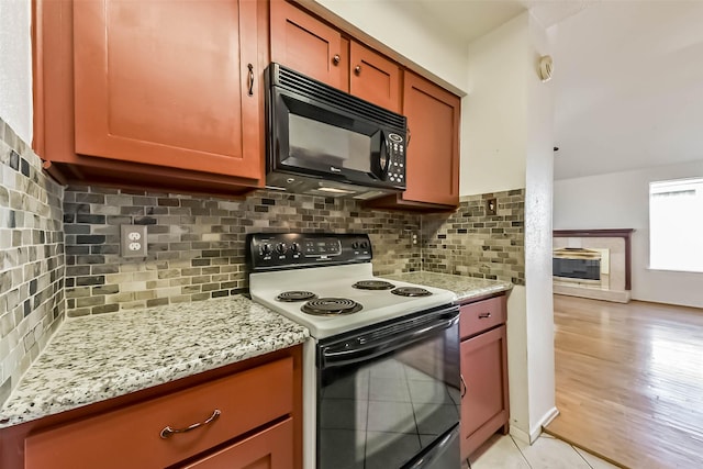 kitchen featuring black appliances, light stone counters, and tasteful backsplash