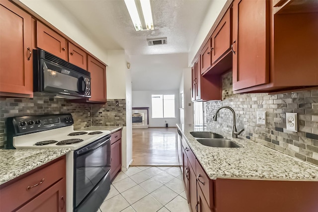 kitchen featuring visible vents, black microwave, electric range oven, light tile patterned floors, and a sink