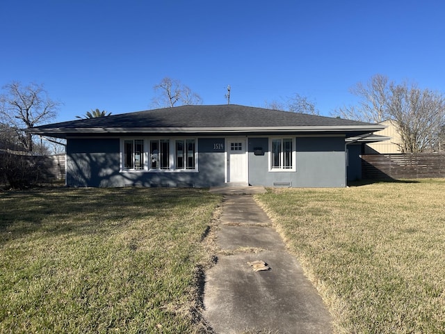 view of front of house featuring a shingled roof, fence, a front lawn, and stucco siding