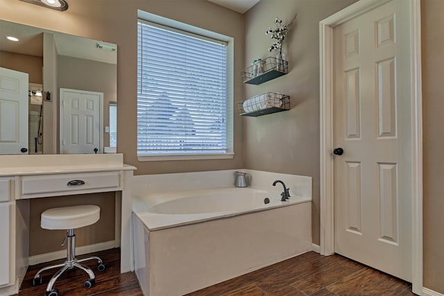 bathroom featuring a bath, baseboards, and wood finished floors