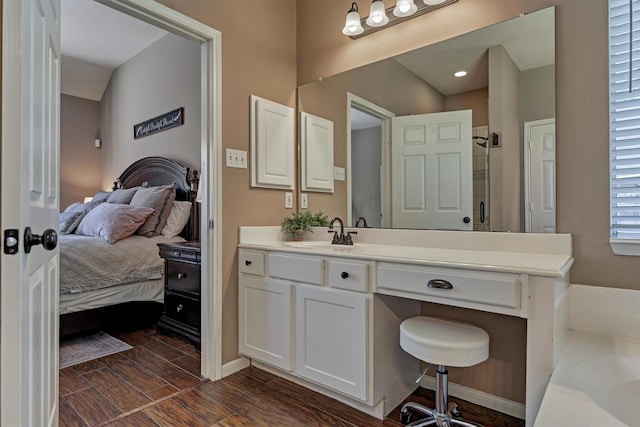 ensuite bathroom featuring walk in shower, baseboards, wood tiled floor, vanity, and ensuite bath