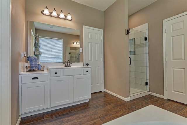 bathroom with vanity, a shower stall, wood finished floors, and baseboards