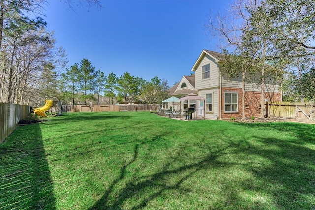 view of yard with a patio area, a playground, and a fenced backyard