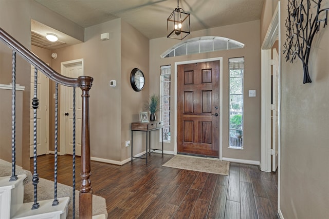 entrance foyer with stairs, dark wood-type flooring, baseboards, and a chandelier