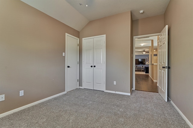 unfurnished bedroom with vaulted ceiling, baseboards, a closet, and carpet floors