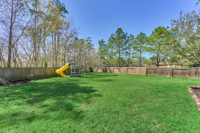 view of yard with a fenced backyard and a playground