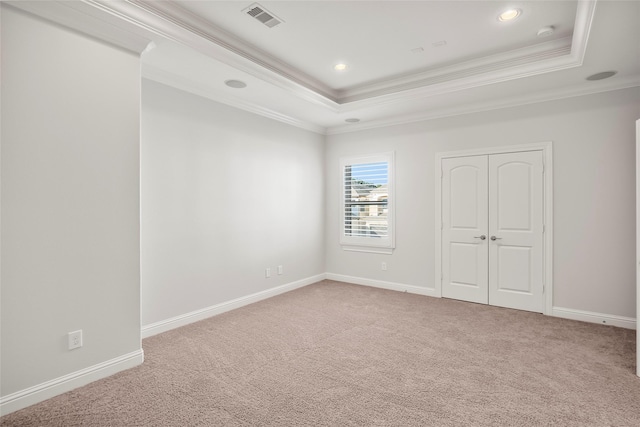 unfurnished room with baseboards, visible vents, a tray ceiling, crown molding, and carpet flooring