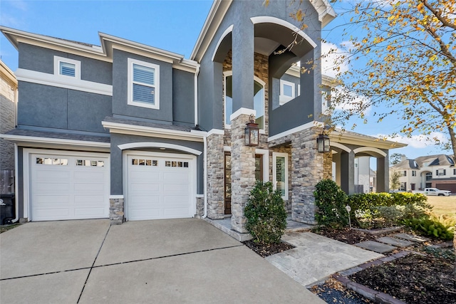 view of front facade featuring stone siding, driveway, and stucco siding