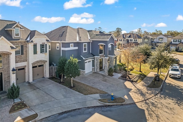 view of front of property featuring a garage, a residential view, stone siding, and driveway