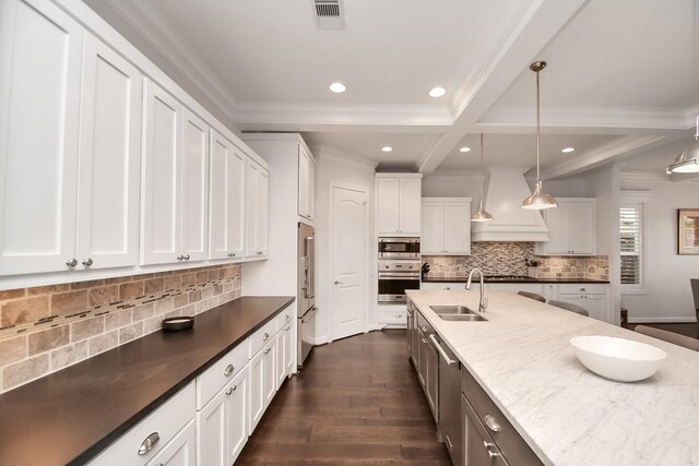 kitchen featuring stainless steel appliances, custom range hood, visible vents, white cabinets, and a sink