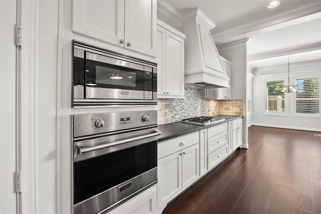 kitchen featuring stainless steel appliances, premium range hood, dark wood-style flooring, white cabinetry, and tasteful backsplash