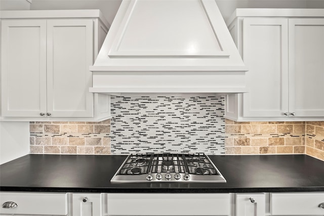 kitchen with dark countertops, white cabinets, stainless steel gas cooktop, and backsplash