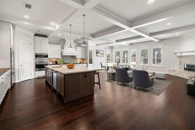 kitchen with dark wood finished floors, stainless steel appliances, tasteful backsplash, visible vents, and a sink