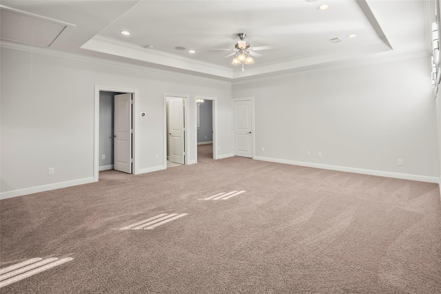 unfurnished bedroom with a raised ceiling, light colored carpet, attic access, ornamental molding, and baseboards