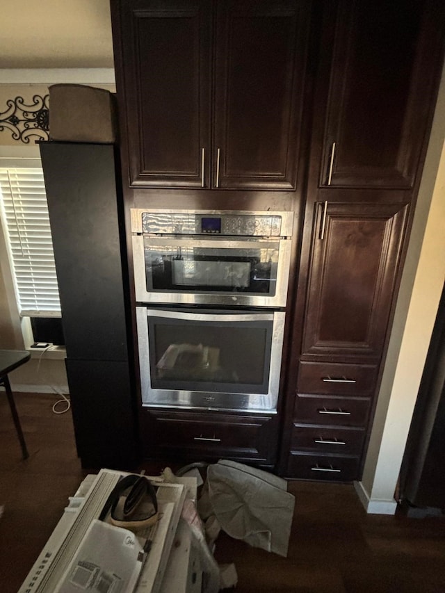 kitchen featuring dark wood-style floors, double oven, baseboards, and dark brown cabinets