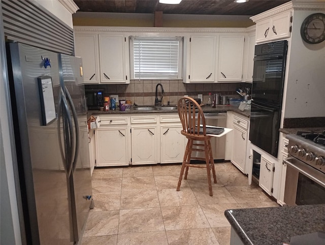 kitchen featuring dark countertops, decorative backsplash, stainless steel appliances, and a sink