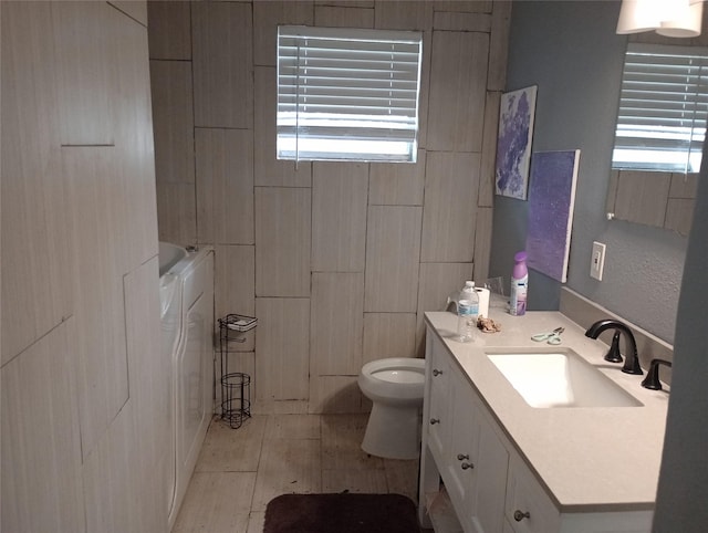 bathroom featuring a healthy amount of sunlight, toilet, separate washer and dryer, and vanity