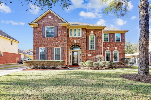 view of front facade with a front yard and brick siding