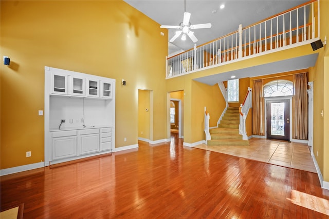 entrance foyer with a ceiling fan, stairs, baseboards, and hardwood / wood-style flooring