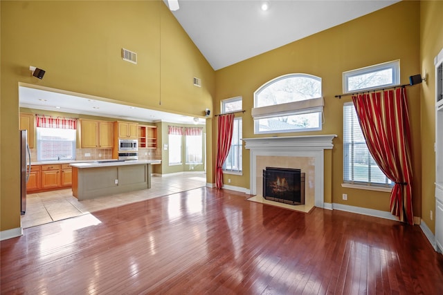 9406 Laurel Wind Ct, Houston, TX 77040 - unfurnished living room featuring high vaulted ceiling, light wood-style floors, and a tiled fireplace